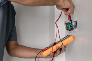 repairman working on an electrical switch with a voltmeter